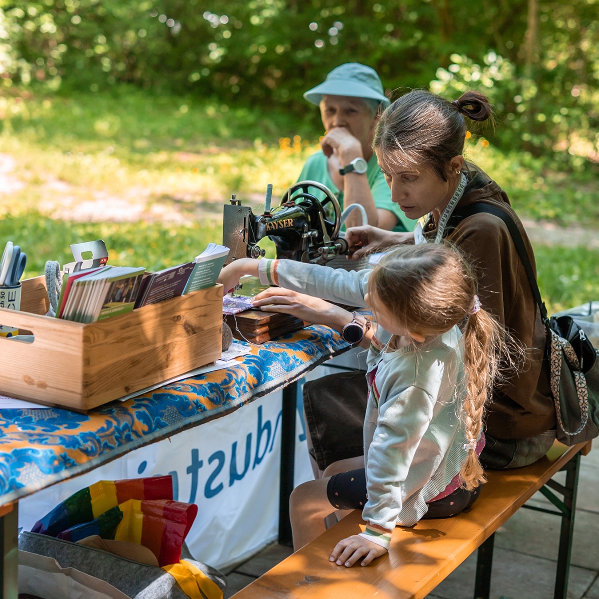 Fau und Kind sitzen an Nähmaschine im Wald